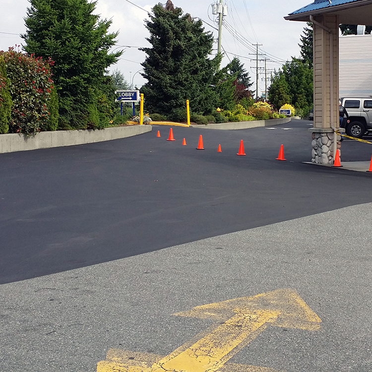 Professional Asphalt Sealcoating Freshly sealcoated asphalt with pylons set up